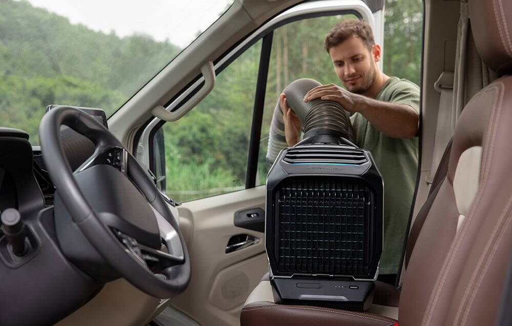 Un bărbat conectează conductele de aer la un aparat de aer condiționat amplasat pe scaunul unei rulote